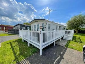 a white house with a white fence on a yard at Beautiful Caravan At Manor Park In Hunstanton Beach, Norfolk Ref 23026H in Hunstanton