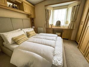 two beds in a room with a couch and a window at Beautiful Caravan At Manor Park In Hunstanton Beach, Norfolk Ref 23026H in Hunstanton