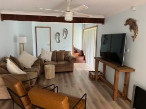 a living room with a couch and a flat screen tv at Paws and Pause at The Bay in Callala Bay