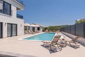 a swimming pool with lounge chairs and a house at Villa Skyora in Trogir