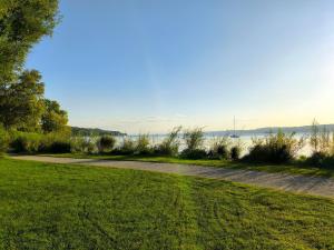 a path through a park with the water in the background at Helle Wohnung in Seenähe in Berg am Starnberger See +9 photos