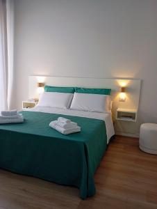 a green and white bed with two towels on it at Letizia B&B in Crotone