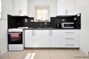 3 Bedroom 2 Bathroom Heathfield Avenue Salamanca 50m في هوبارت: مطبخ أبيض مع دواليب بيضاء وميكرويف +17 صورة
