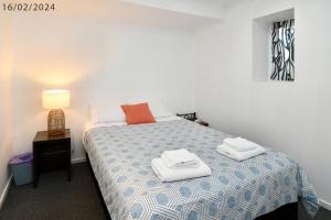 3 Bedroom 2 Bathroom Heathfield Avenue Salamanca 50m في هوبارت: غرفة نوم بها سرير عليه منشفتان