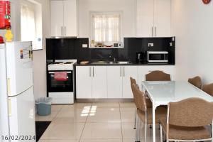 3 Bedroom 2 Bathroom Heathfield Avenue Salamanca 50m في هوبارت: مطبخ مع دواليب بيضاء وطاولة مع كراسي