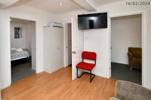 3 Bedroom 2 Bathroom Heathfield Avenue Salamanca 50m في هوبارت: غرفة معيشة مع كرسي احمر وغرفة نوم