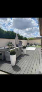a deck with two chairs and a couch and an umbrella at Maison calme avec piscine privée in Argenteuil