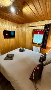 a bedroom with a large white bed in a wooden room at Chalet Le Salers 10pers Le Mont Dore in Mont-Dore