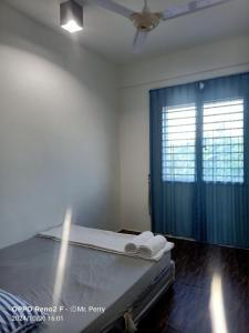 a bedroom with a bed with a blue curtain and a window at SP HOMESTAY Taman SURIA INDAH KOTA MARUDU SABAH in Kampong Sorosob