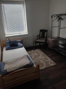 a bedroom with a bed and a chair and a window at Slnečný apartmán u Klaudii in Levice