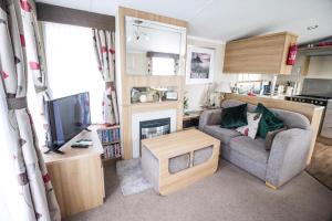 a living room with a couch and a tv at Beautiful 8 Berth Caravan For Hire At Seashore Haven Park In Norfolk Ref 22039C in Great Yarmouth