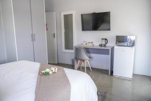 a bedroom with a bed and a table and a kitchen at Alu Boutique Hotel and Conference in Roodepoort