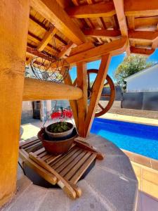 a planter sitting on a bench under a wooden pergola at Maravillosa villa con piscina y barbacoa in Puigventos