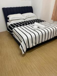 a large bed with black and white sheets and pillows at De'Garden 12 in Alor Setar