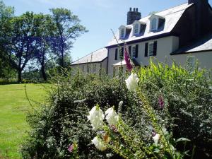 Una casa blanca con flores delante. en Tor Royal Farm House, en Princetown