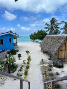 a beach with a blue house and the ocean at Te Fare Ninamu Maupiti in Te-Fare-Arii