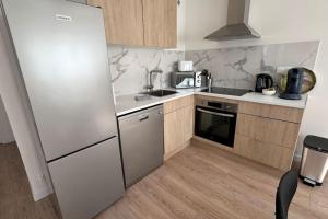 eine Küche mit Edelstahlkühlschrank und Holzschränken in der Unterkunft Appart cozy dans le centre-ville, 6 pers in Neuilly-Plaisance + 14 Fotos