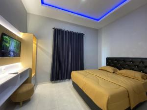 a bedroom with a bed and a tv on a wall at Hotel Agro Tawangmangu in Tawangmangu