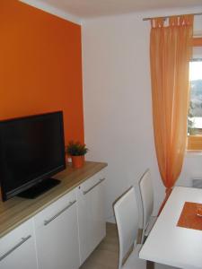 a living room with a tv and a table with chairs at Apartmán Linda in Lipno nad Vltavou