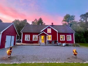a red house with two chairs in front of it at Christiansfrid - Humlaryd in Eringsboda