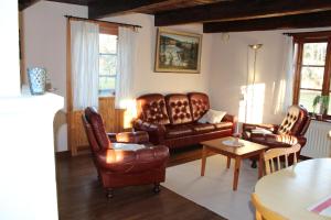 a living room with leather furniture and a table at Lilla Sandereds Gård in Loftahammar
