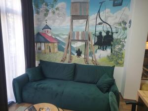 a living room with a blue couch in front of a painting at Apartman Djurdja in Divčibare