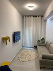 a living room with a couch and a tv on a wall at SimOtel Downtown Suite in Thessaloniki