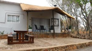 una pequeña casa blanca con techo de paja en Refreshing Mountain FarmStay w Boma,Pool,Hikes,Obstacle Course, en Magaliesburg