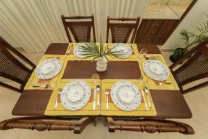a wooden table with plates and utensils on it at Candolim's New 3BHK-Azure Luxury Penthouse Next to Starbucks, 6 minutes walk to Beach - By Lembranca in Candolim
