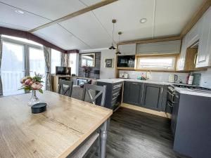 a kitchen with a wooden table and a dining room at Beautiful Caravan With Decking At Naze Marine Park, Sleeps 8 Ref 17341Br in Walton-on-the-Naze +12 photos