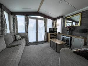 a living room with a couch and a tv at Beautiful Caravan With Decking At Naze Marine Park, Sleeps 8 Ref 17341Br in Walton-on-the-Naze