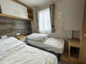 two beds in a small room with a window at Beautiful Caravan With Decking At Naze Marine Park, Sleeps 8 Ref 17341Br in Walton-on-the-Naze