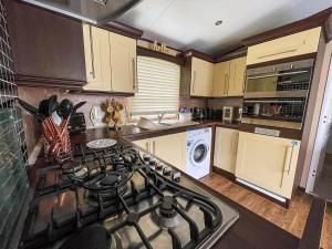 a kitchen with a stove top oven next to a counter at Beautiful Caravan At Manor Park In Hunstanton Beach, Norfolk Ref 23026H in Hunstanton +12 photos