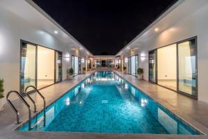 einen Innenpool in einem Gebäude mit Fenstern in der Unterkunft T M L-Manor House 6 bedroom-independent swimming pool and powerful KTV in Ban Huai Yai