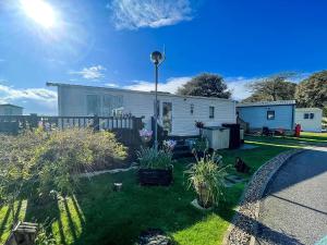 a small white house with a yard with plants at Brilliant Caravan With A Partial Sea View In Suffolk Ref 32026Az in Lowestoft