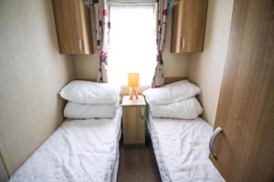 two beds in a small room with a window at Beautiful 8 Berth Caravan For Hire At Seashore Haven Park In Norfolk Ref 22039C in Great Yarmouth