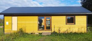 a small yellow house with a dog in the window at Rapla Ratsakeskuse puhkemaja, Rapla Equestrian Centre holidayhouse in Libadu