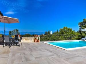 a patio with a table and chairs and a swimming pool at Wonderful Brsec Apartments with Sea View and Shared Pool in Brseč