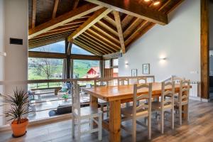 a dining room with a wooden table and chairs and a large window at Casa 8plazas, 7km de la playa La Franca, Asturias in Boquerizo