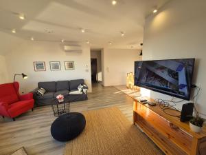 a living room with a couch and a large flat screen tv at Jókai Corner Apartment in Debrecen