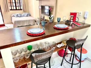 a kitchen with a bar with two chairs and wine glasses at Studio pé na areia com área de churrasco privativa in Bertioga +5 photos
