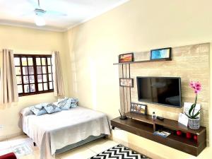 a bedroom with a bed and a flat screen tv at Studio pé na areia com área de churrasco privativa in Bertioga