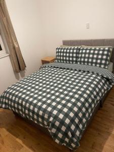 een bed met een zwart-wit geruite deken bij Morrisons 2 weeks plus city centre 2 bedroom Apt in Aberdeen