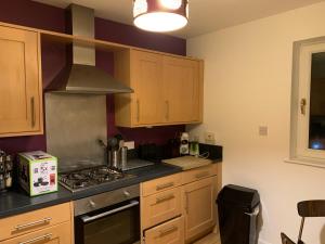 een keuken met houten kasten en een kookplaat met oven bij Morrisons 2 weeks plus city centre 2 bedroom Apt in Aberdeen +8 foto's