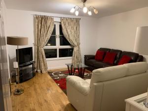 een woonkamer met een bank en een televisie bij Morrisons 2 weeks plus city centre 2 bedroom Apt in Aberdeen