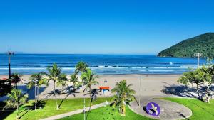a view of a beach with palm trees and the ocean at Studio pé na areia com área de churrasco privativa in Bertioga