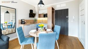 a kitchen and dining room with a table and blue chairs at Wonder Home- Sienkiewicza 9, ścisłe centrum, blisko deptaka in Świeradów-Zdrój