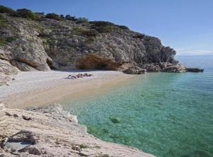 a group of people laying on a beach near the water at Chic and Cozy Brsec Apartment with Sea View in Brseč +4 photos