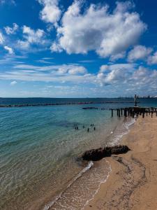 a beach with people in the water and a pier at La Perla Apartment in Taranto