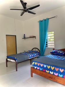 two beds in a room with a ceiling fan at roomstay batu buruk in Kuala Terengganu
